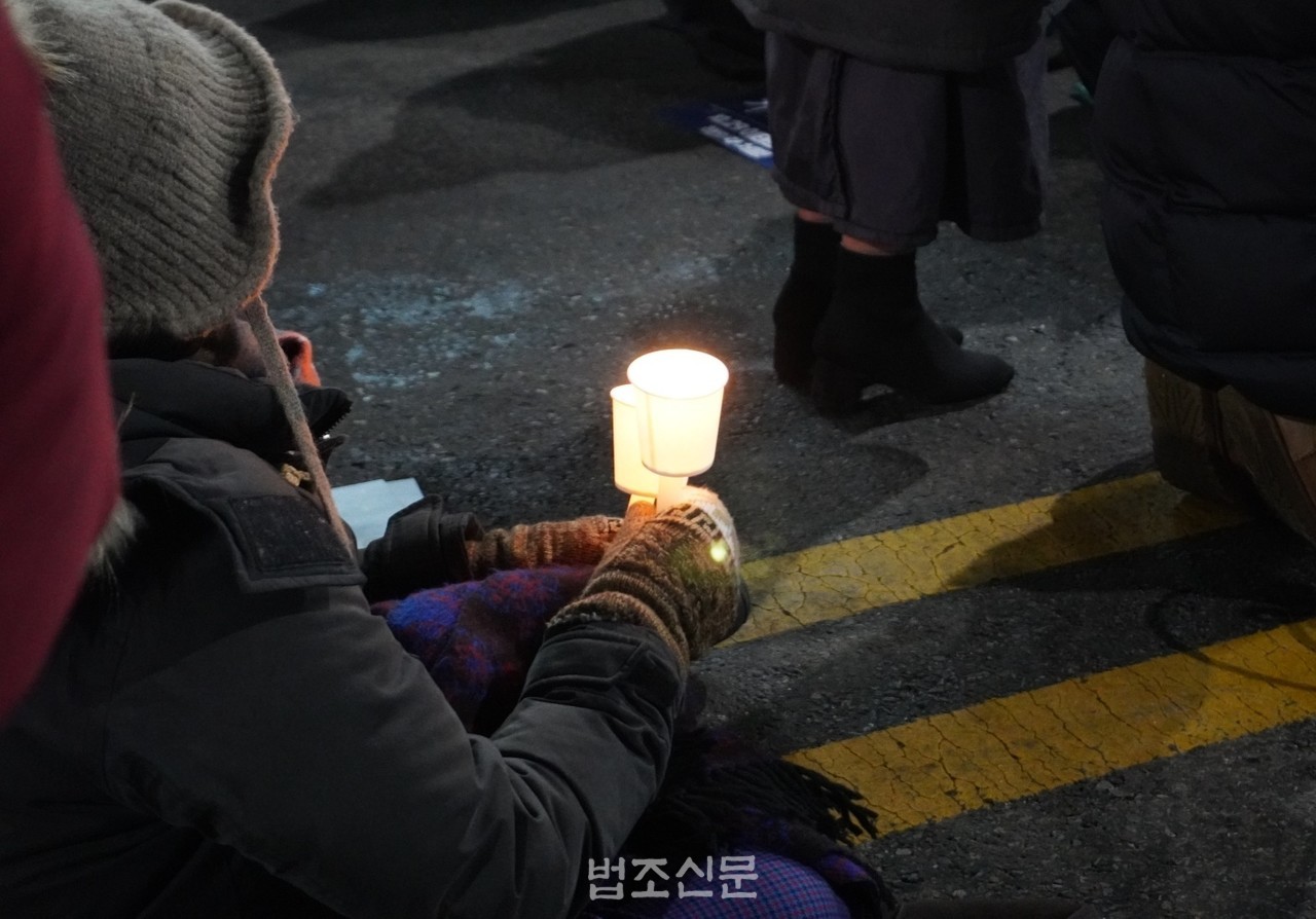 △ 한 시민이 16일 '10.29 이태원 참사 49일 시민추모제'가 열린 서울 용산구 이태원역 앞 도로 위에 앉아 희생자들을 추모하고 있다.